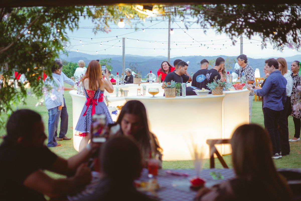 Bar iluminado do Celeiro Monte Alto com convidados ao entardecer