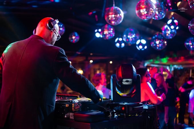 DJ de costas comandando a pista sob os globos