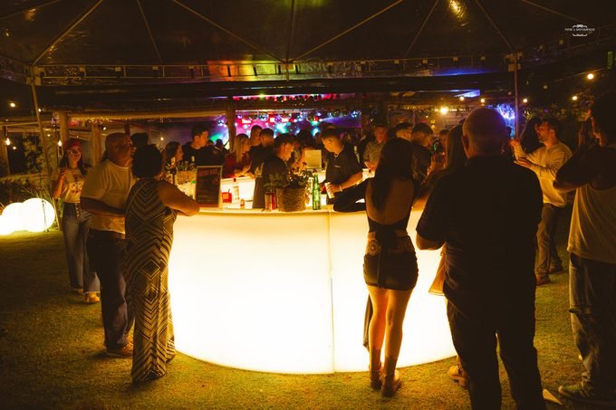 Bar iluminado cheio de convidados durante a noite