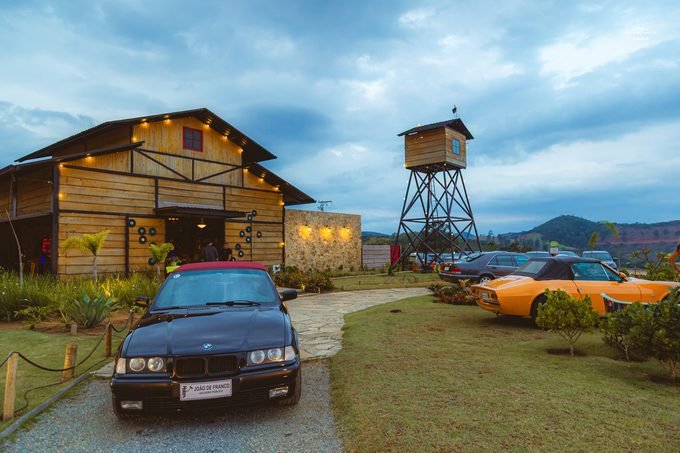 Celeiro Monte Alto iluminado ao entardecer com carros clássicos na entrada