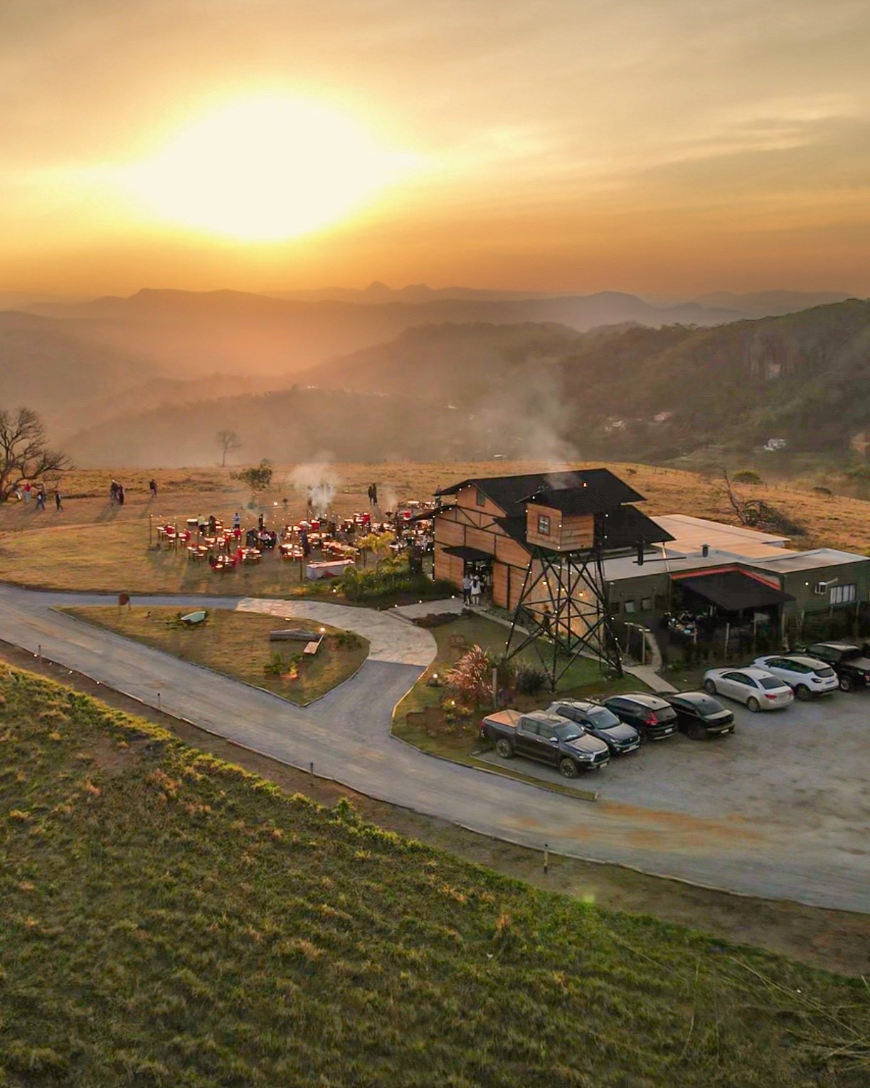 Vista aérea do Celeiro Monte Alto ao pôr do sol, com as montanhas ao fundo