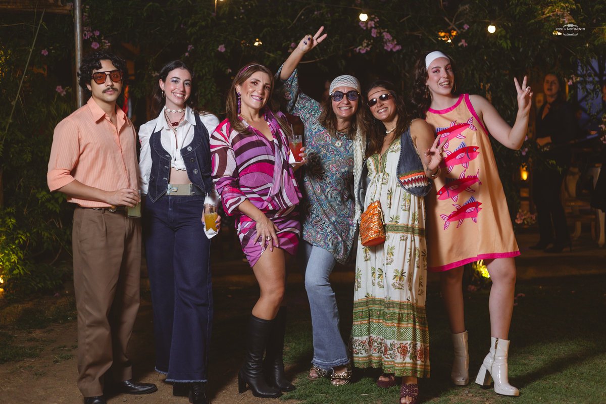 Grupo de convidados caracterizados com roupas dos anos 70