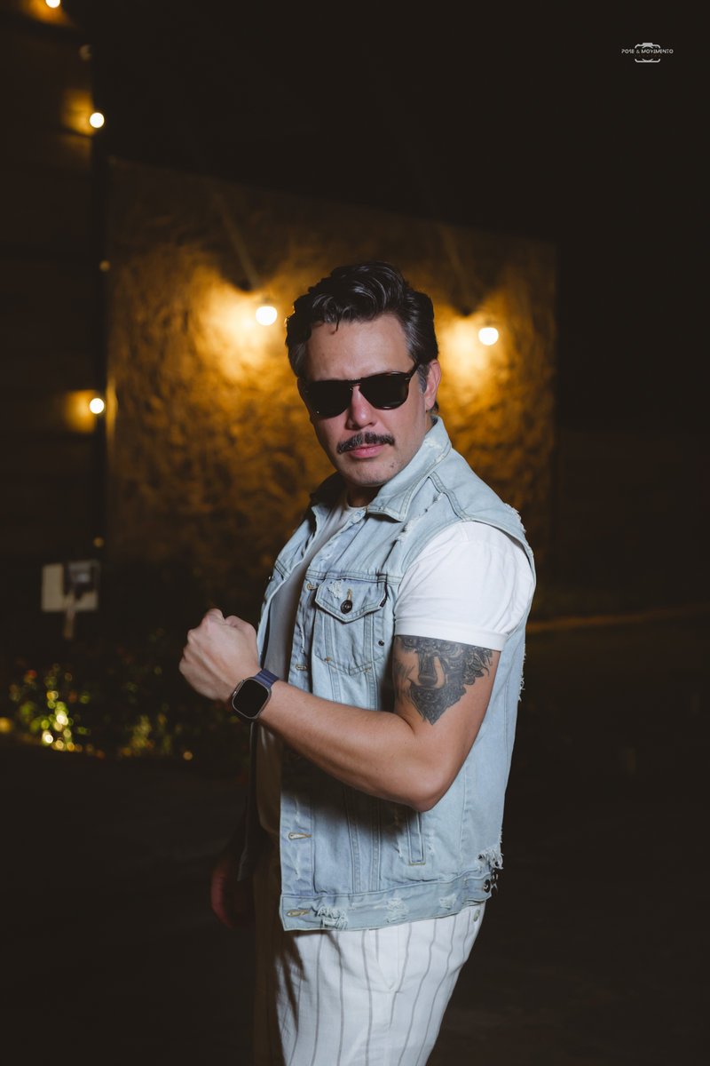 Convidado com colete jeans e bigode posando à noite
